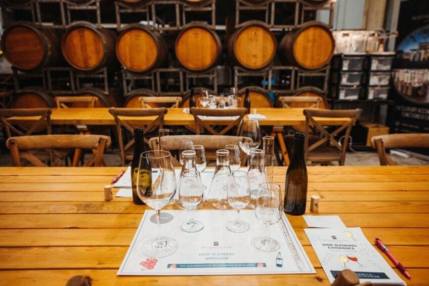 A wine tasting setup with empty wine glasses, a tasting sheet, and a corkscrew on a wooden table. 2