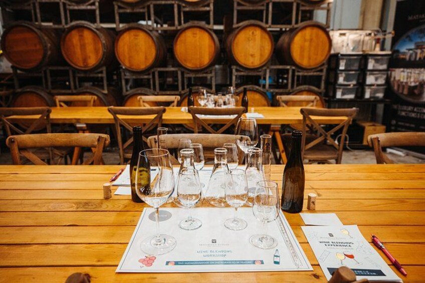 A wine tasting event with empty wine glasses on a table, surrounded by wooden barrels in the background. 2