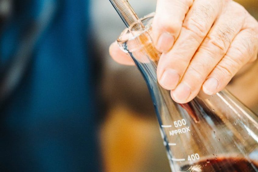 A person holding a graduated glass measuring cylinder with liquid. 3