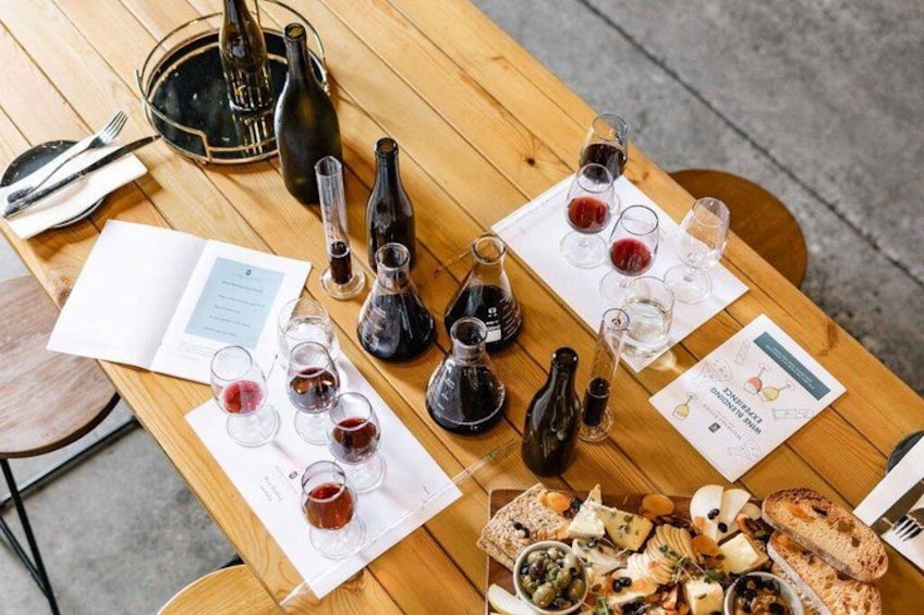 A wooden table with wine bottles, glasses, a menu, and a charcuterie board. 1