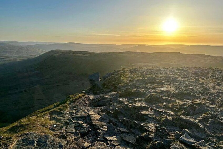 A mountainous landscape with a clear sky and the sun setting in the background. 3