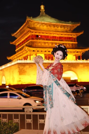 Une personne vêtue d’un costume traditionnel, avec une pagode en arrière-plan. 1
