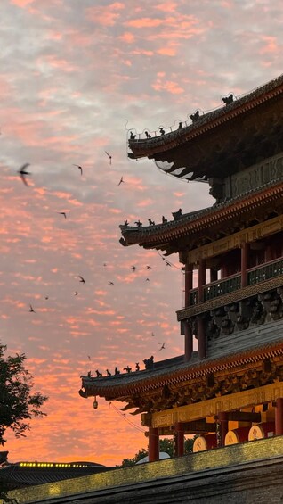 Un bâtiment traditionnel à plusieurs niveaux, orné de décorations élaborées sur le toit, avec un ciel flamboyant au coucher du soleil. 3
