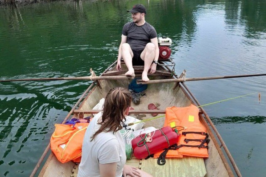 A small boat on calm water with a person sitting at the front and another person standing at the back. 3