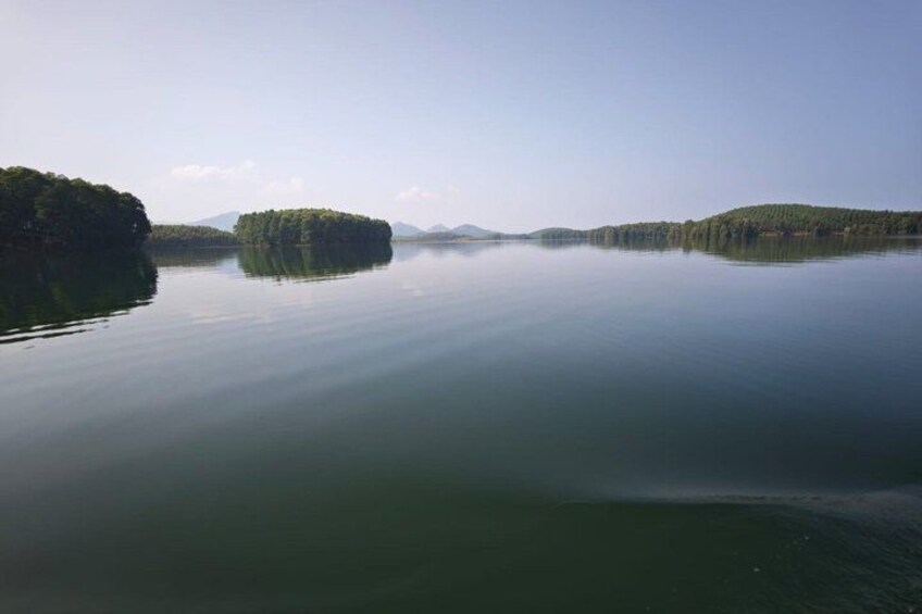A calm lake with two small islands surrounded by trees. 4
