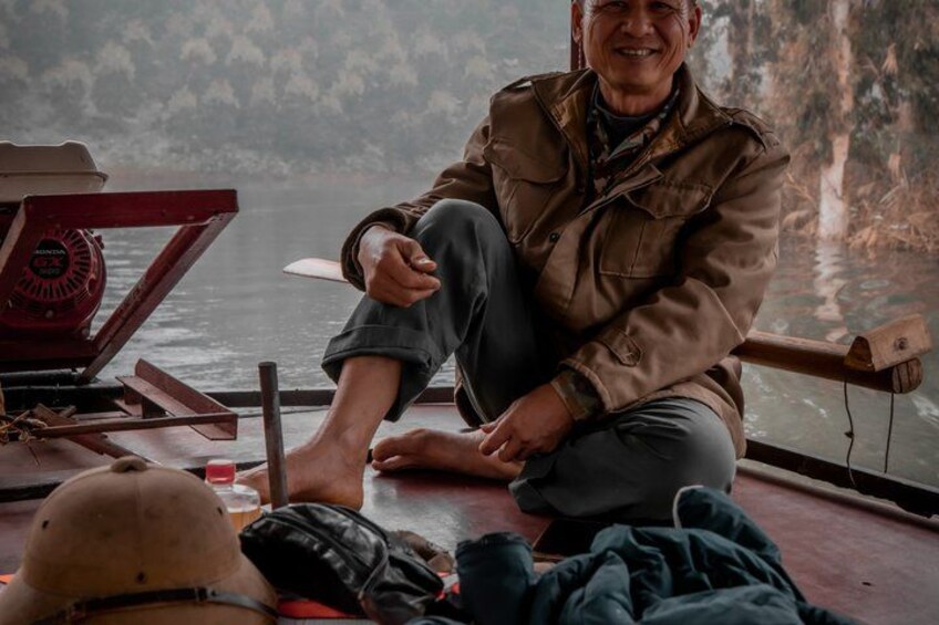 A person sitting on a boat with a motor and a rocky landscape in the background. 2