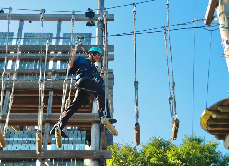 A person climbing a wooden obstacle course with ropes and pulleys. 5