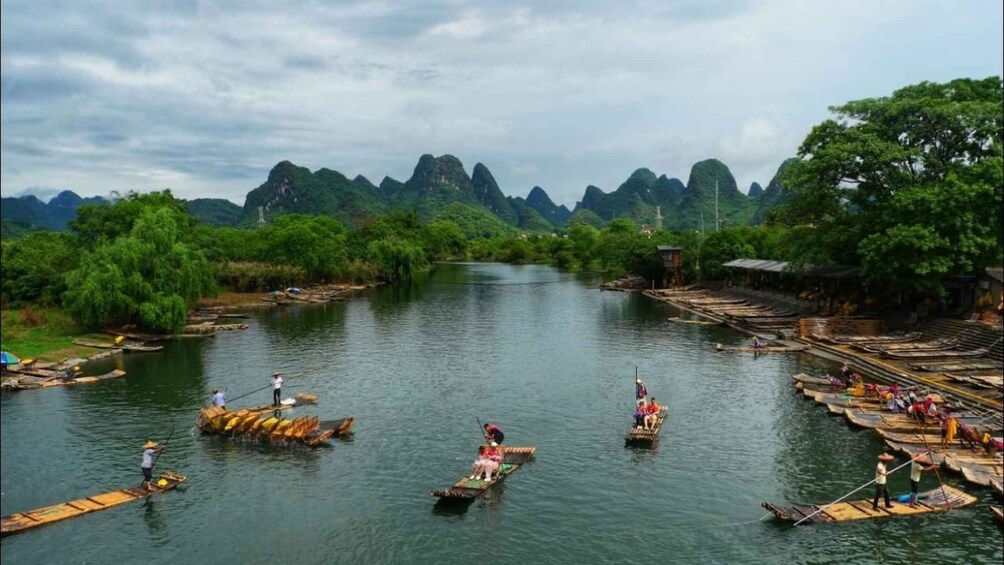 A river with people paddling on traditional boats, surrounded by lush greenery and mountains. 3