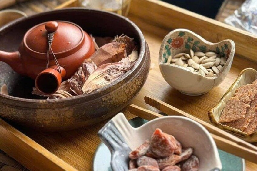 A traditional tea set with a teapot, cups, and a tray with various items like nuts and dried meat. 3