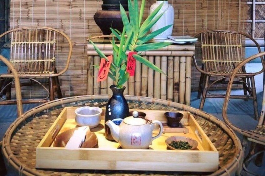 A bamboo chair, a wicker chair, a bamboo table, a tray with tea utensils, and a potted plant. 1