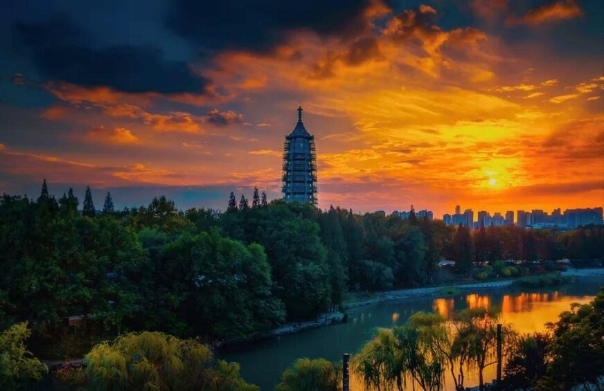 Une pagode, une rivière et la silhouette d’une ville au coucher du soleil. 1