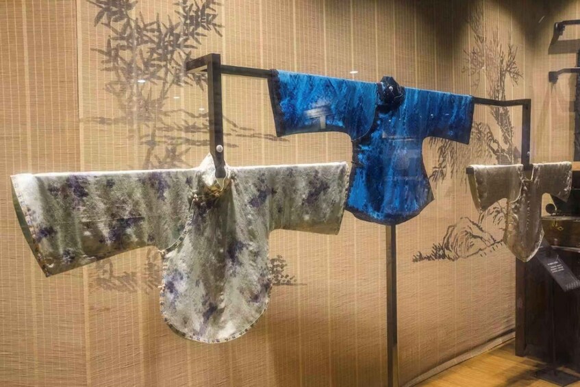 Un vêtement traditionnel japonais exposé sur un présentoir, avec un décor de bambous en arrière-plan. 3