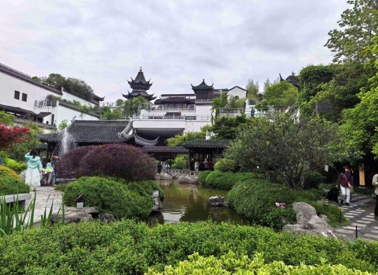 Un jardin chinois traditionnel avec un étang, des bâtiments de style pagode et une végétation luxuriante. 1