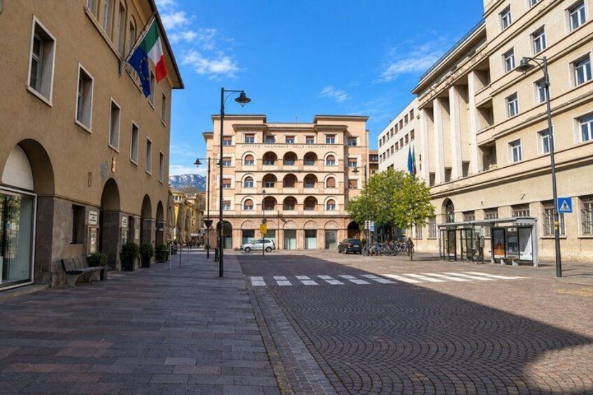 A street with buildings, a crosswalk, and a bus stop. 2