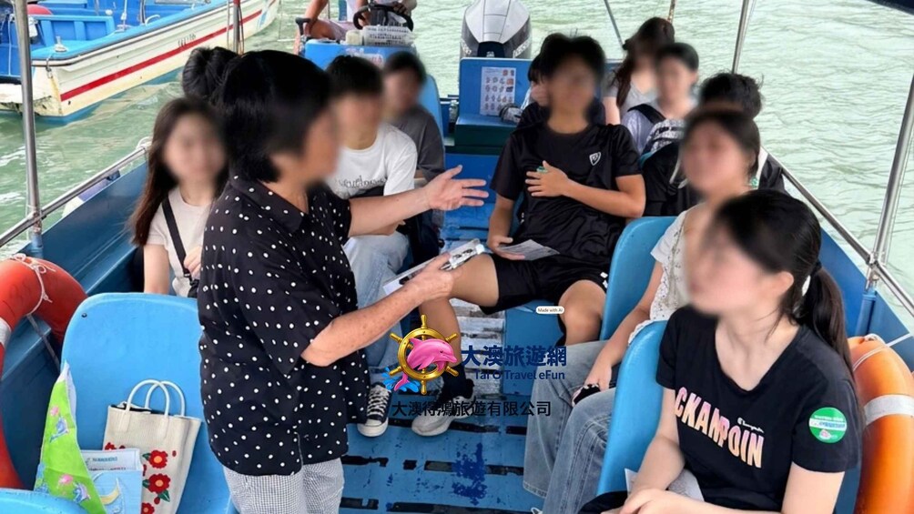 Un groupe de personnes se trouve à bord d’un bateau, certaines sont assises, d’autres sont debout, et un guide accompagne le groupe. 1