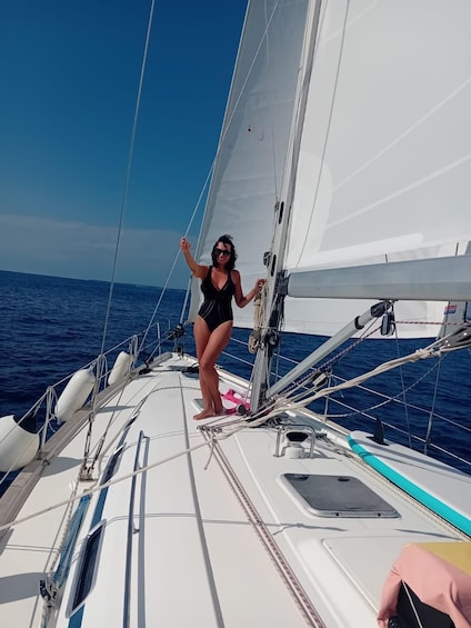 Eine Person auf einem Segelboot vor blauem Himmel und ruhiger See. 3