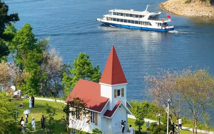 A white church with a red roof, a river, and a blue and white boat. 3
