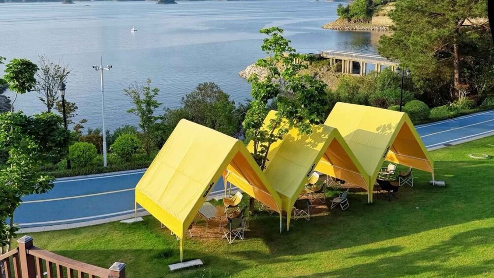 A lakeside camping area with yellow tents and a paved road. 1