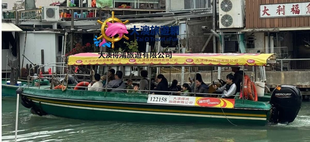 Un bateau transportant des passagers, orné d’un logo représentant un dauphin, et portant une enseigne indiquant « Tai O Travel ». 1