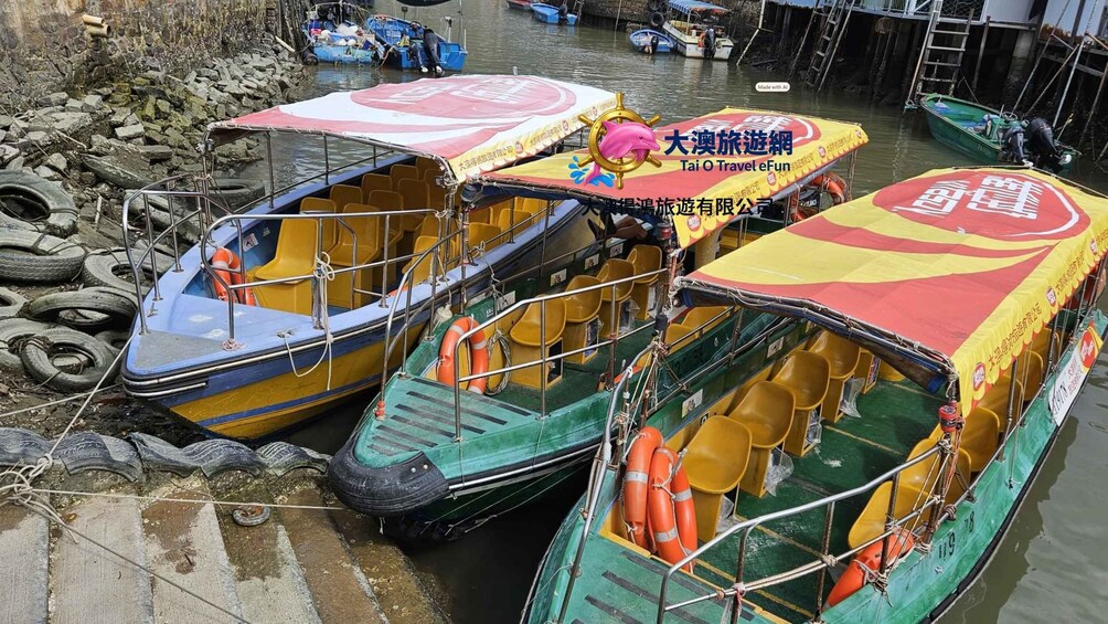 Trois bateaux aux couleurs vives étaient amarrés à un quai, à proximité duquel étaient empilés des pneus. 4