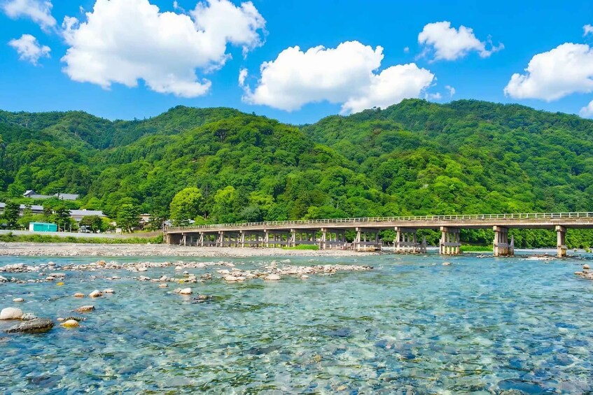 Un río de aguas cristalinas, un puente y una montaña arbolada en el fondo. 2