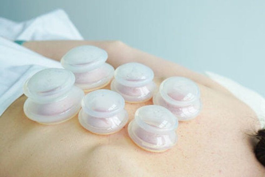 A person's back with several transparent, round objects placed on it. 5