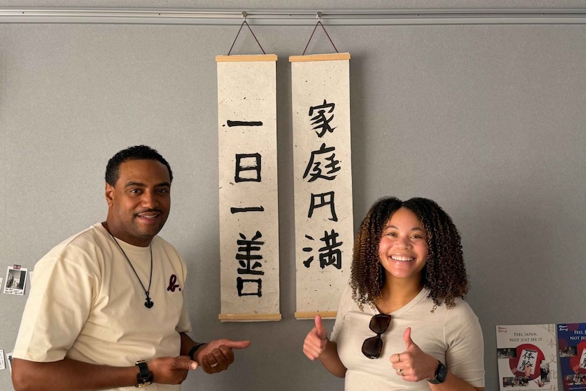 Deux personnes pointent du doigt des banderoles verticales ornées de caractères japonais. 1