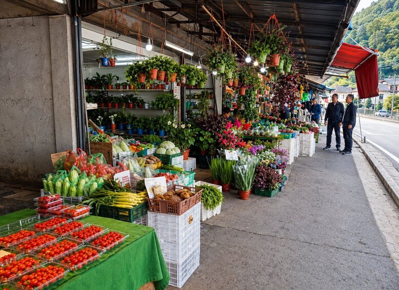 Ein belebter Markt im Freien mit verschiedenen Ständen, auf denen frisches Obst, Blumen und Pflanzen verkauft werden. 5