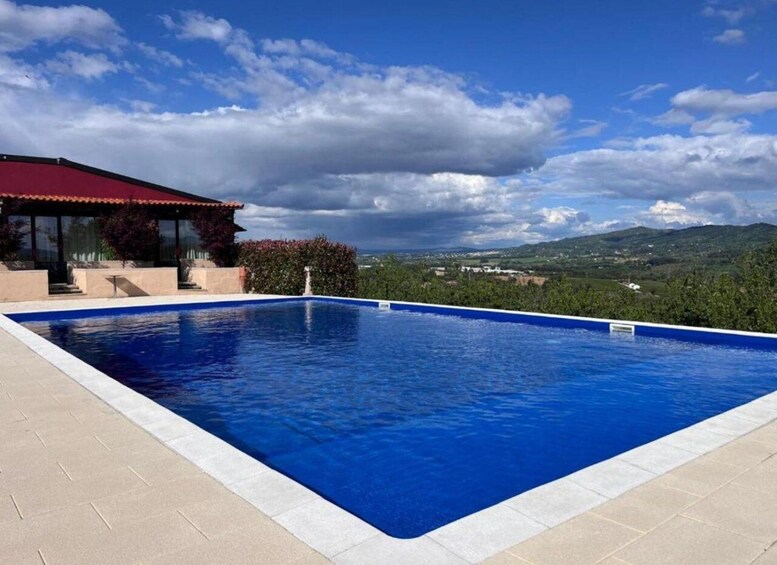 A swimming pool with a view of a house and distant hills. 1