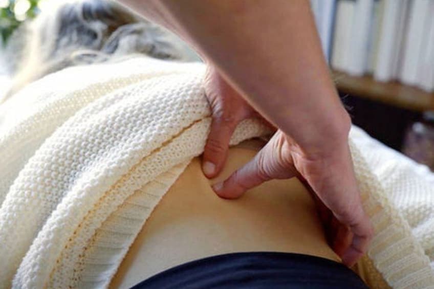 A person receiving a massage with a white towel covering their upper body. 4