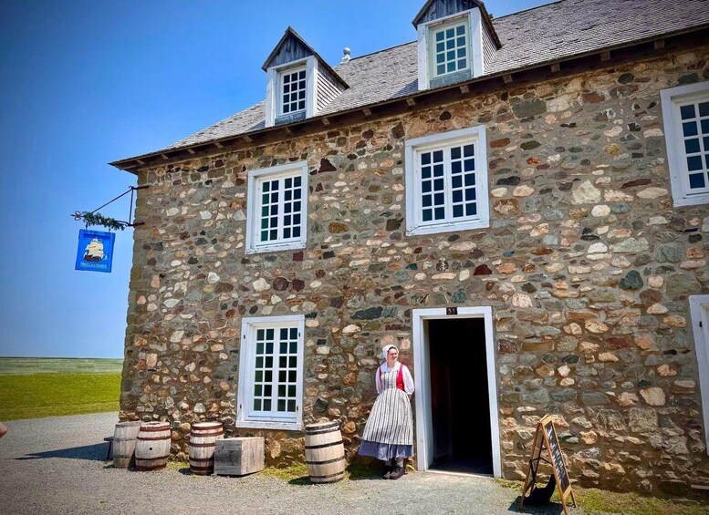 Un bâtiment en pierre, avec un drapeau, des barils et une personne vêtue d’un costume traditionnel. 5