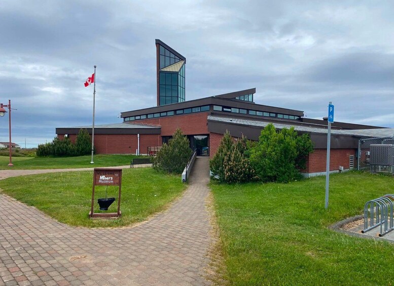 Un bâtiment moderne doté d’une façade en verre, d’un drapeau et d’une enseigne accueillant les visiteurs du musée. 1