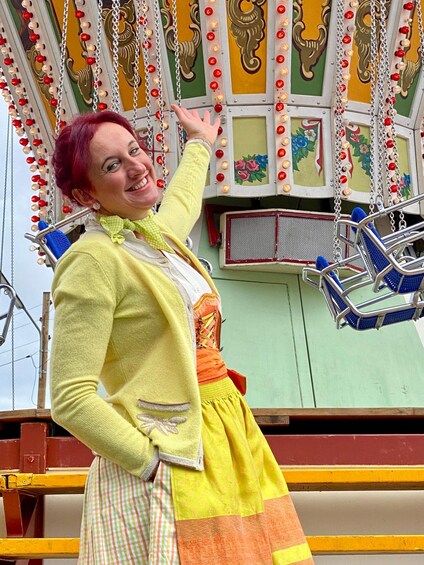 Una persona con suéter amarillo y falda naranja parada en un columpio decorado. 1