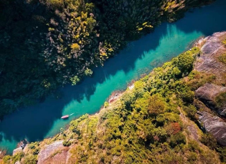 A river with clear turquoise water, surrounded by dense green forest and rocky terrain. 3