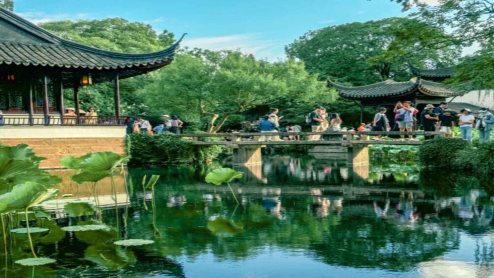 A traditional pavilion with a tiled roof, a stone bridge over a pond with lily pads, and lush greenery in the background. 2