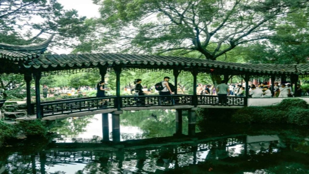 A traditional pavilion over a reflective water body with people walking around. 3