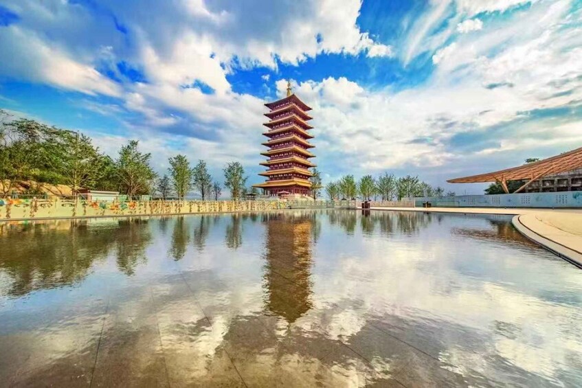 Un bâtiment de style pagode se reflète dans une étendue d’eau calme, entouré d’arbres et sous un ciel dégagé. 3