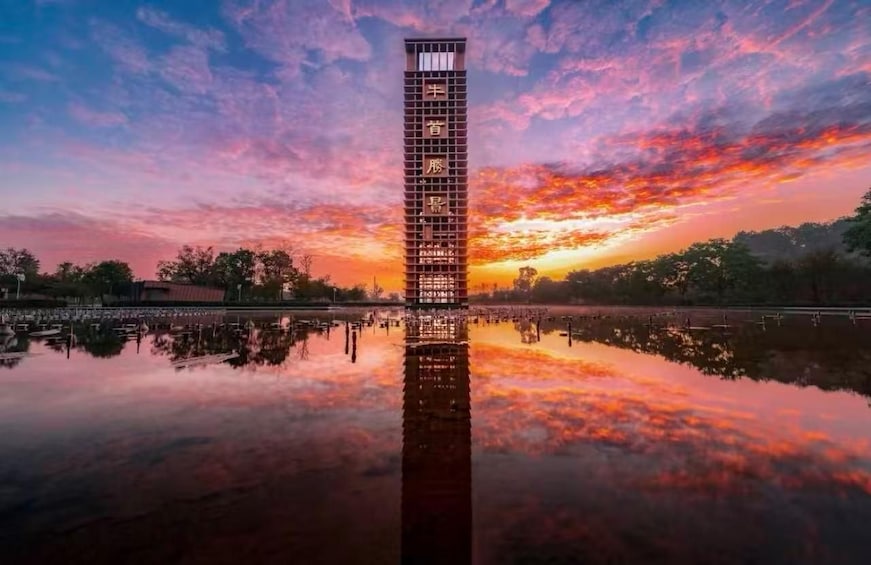 Une tour se reflétant sur une étendue d’eau calme, avec un ciel au coucher du soleil. 1