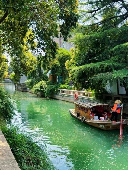 Un bateau en bois traditionnel sur une rivière, entouré d’une végétation luxuriante et d’un pont de pierre. 4