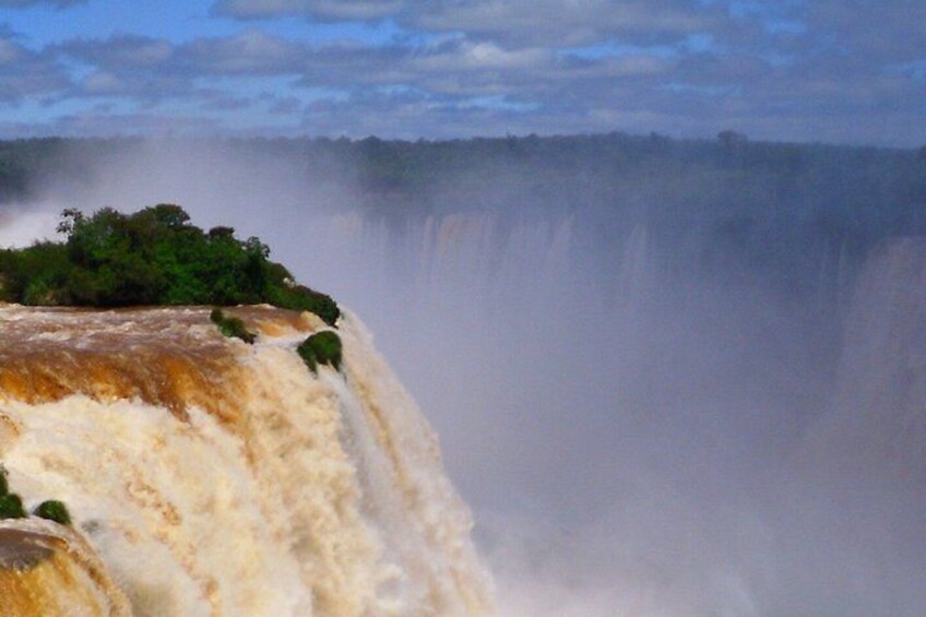 A large waterfall with a cliff edge and dense greenery at the top. 3