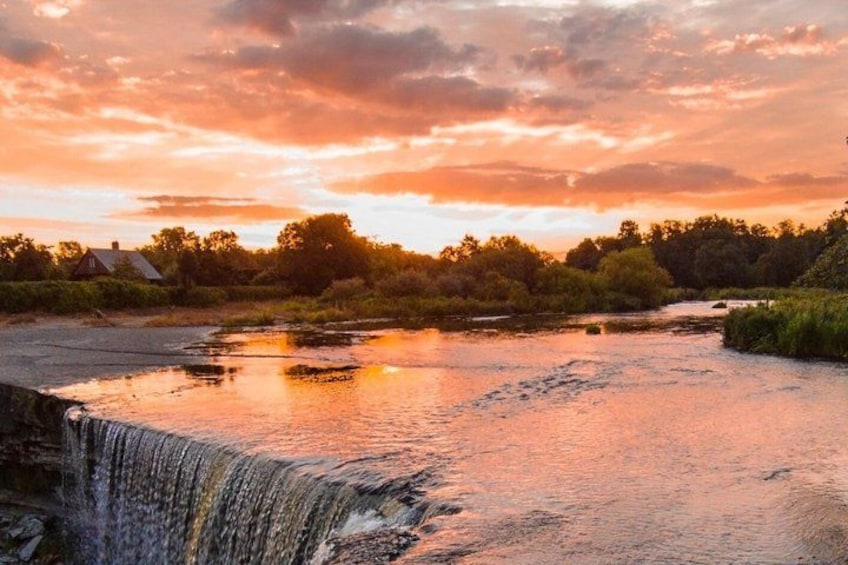 A river with a waterfall, surrounded by trees and a sunset sky. 1