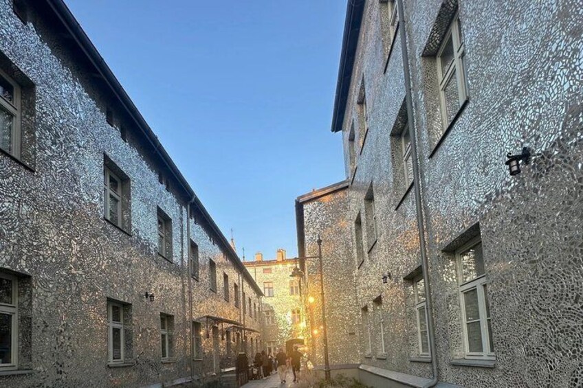 A narrow street with buildings covered in textured material, a clear sky, and a distant light source. 5