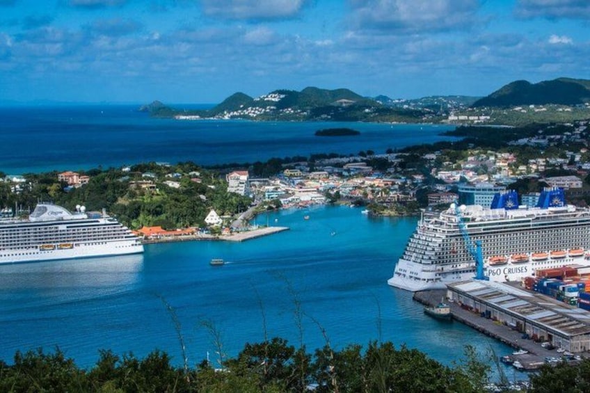 A cruise ship docked at a port with a clear view of the surrounding coastline and hills. 1