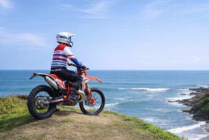 A person on a dirt bike by the ocean. 1