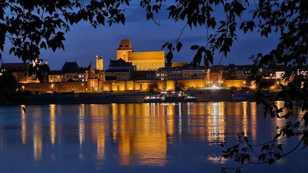 A historic cityscape at dusk with illuminated buildings reflecting on the water. 3