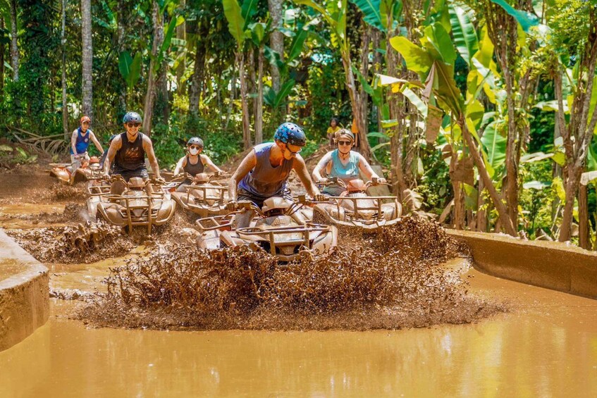 Menschen fahren mit Quads durch eine schlammige Wasserfurte. 4