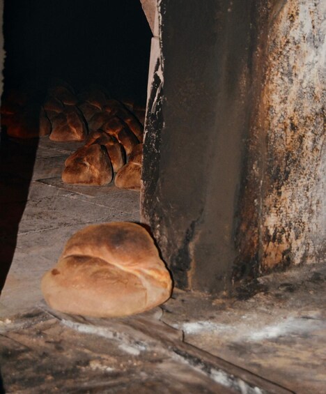Ein rustikaler Backofen aus Stein mit darin gebackenem Brot. 3