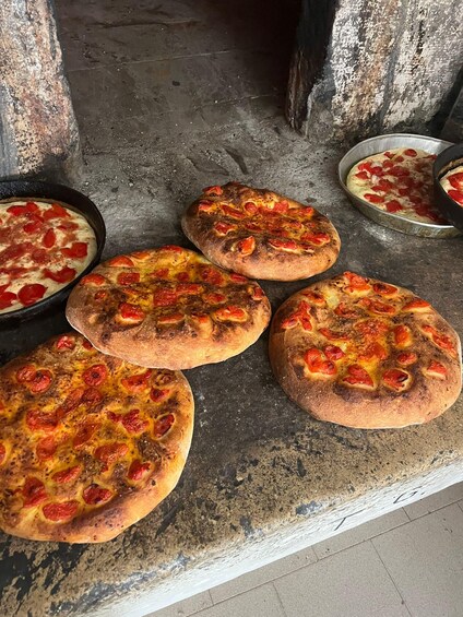 Vier Pizzen mit Belag auf einer Steinfläche. 2