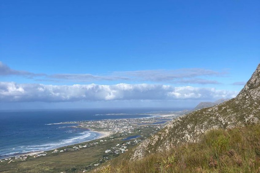A coastal landscape with a clear sky, a beach, and a hilly terrain. 4