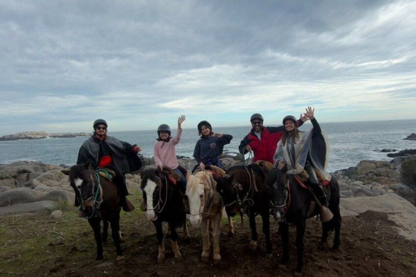 A group of people on horseback by a rocky coastline. 2